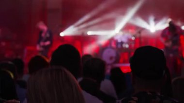 Sahnenin önündeki parlak spot ışıklarıyla konserdeki kalabalık siluetleri. İnsanlar bando konserinde canlı müzikten hoşlanırlar. Müzik festivalinde müzisyenler ve hayranlarla konser salonu