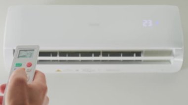 Klima sıcaklığını uzaktan kumandayla ayarlıyorum. Uzaktan kumandalı ve apartmandaki iklim sisteminde rahat sıcaklık ayarlı.