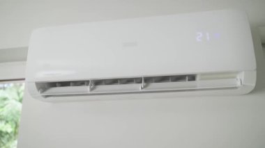 Modern apartmanın beyaz duvarına klima monte edilmiş. Oturma odasında rahat sıcaklık için soğutma sistemi