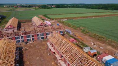 Banliyö bölgesindeki yeni ev inşaatı projesinin havadan görüntüsü. İnşaat alanında kiriş, kiriş ve direkli ahşap çatı iskeleti var. Küçük bir kasabada yeni bir mahalle imalatı