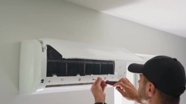 Klima bakımı. Erkek teknisyen oturma odasındaki iklim sistemini tamir ediyor. İnsan saç kreminin filtrelerini temizliyor.