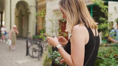 Şehir hayatı ile çevrili, hareketli şehir caddesinde yürürken akıllı telefonuna dalmış bir kadın. Avrupa 'da cep telefonu kullanan kadın gezgin