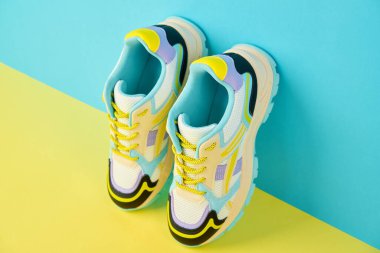 Parlak arka planda renkli aksanlı beyaz spor ayakkabılar renkli arka planda bir çift şık spor ayakkabısı. Mağaza reklamı için stüdyo fotoğrafı, yaratıcı minimalist stil.