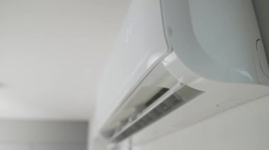 Modern apartmanın beyaz duvarına klima monte edilmiş. Oturma odasında rahat sıcaklık için soğutma sistemi