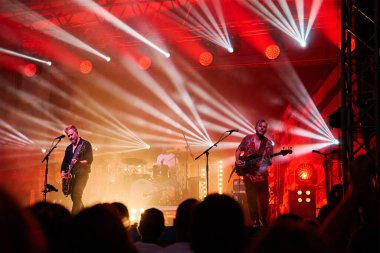 Sahnenin önündeki parlak spot ışıklarıyla konserdeki kalabalık siluetleri. İnsanlar bando konserinde canlı müzikten hoşlanırlar. Müzik festivalinde müzisyenler ve hayranlarla konser salonu