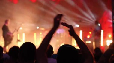 Sahnenin önündeki parlak spot ışıklarıyla konserdeki kalabalık siluetleri. İnsanlar bando konserinde canlı müzikten hoşlanırlar. Müzik festivalinde müzisyenler ve hayranlarla konser salonu