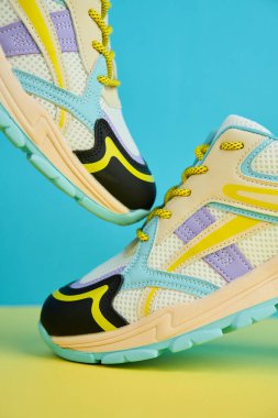 Parlak arka planda renkli aksanlı beyaz spor ayakkabılar renkli arka planda bir çift şık spor ayakkabısı. Mağaza reklamı için stüdyo fotoğrafı, yaratıcı minimalist stil.