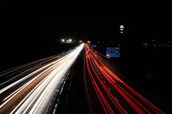 stock image Light trails on the highway at night and McDonalds logo with McCafe sign. Roadside service. Wroclaw, Poland - February 9, 2024