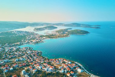 Deniz kıyısına yakın renkli binaları olan kıyı kasabasının havadan görünüşü. Adriyatik Denizi 'nde kırmızı çatı evleri ve adaları olan yaz tatili için turistik bir şehir. Hırvatistan 'ın Rogoznica kasabasının panoramik manzarası