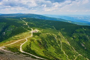 Yeşil dağ vadisinin güzel panoramik manzarası Sniezka 'nın zirvesine ve Polonya' nın Karpacz kentindeki yürüyüş yapan turistlere uzanan dolambaçlı dağ patikası. Seyahat turizmi ve yürüyüş konsepti