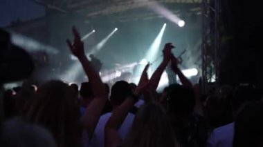 Sahnenin önündeki parlak spot ışıklarıyla konserdeki kalabalık siluetleri. İnsanlar bando konserinde canlı müzikten hoşlanırlar. Müzik festivalinde müzisyenler ve hayranlarla konser salonu