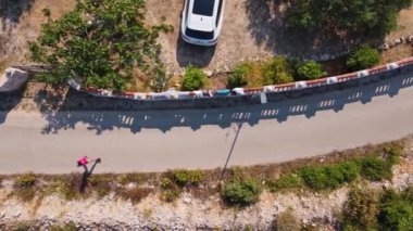 Virajlı köy yolunda koşan kadının hava görüntüsü. Kadın koşucu sabah koşuyor.