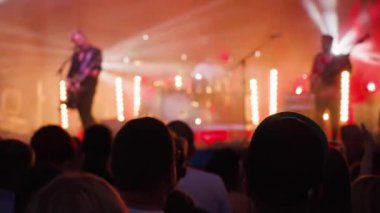 Sahnenin önündeki parlak spot ışıklarıyla konserdeki kalabalık siluetleri. İnsanlar bando konserinde canlı müzikten hoşlanırlar. Müzik festivalinde müzisyenler ve hayranlarla konser salonu