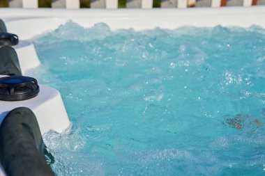 Close-up shot bubbling water in hot tub with headrests. Blue water in jacuzzi for relaxing and refreshing spa experience clipart