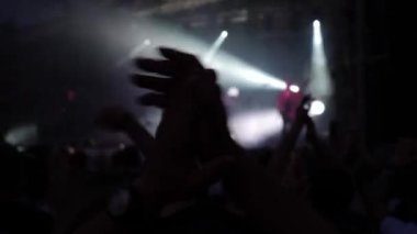 Sahnenin önündeki parlak spot ışıklarıyla konserdeki kalabalık siluetleri. İnsanlar bando konserinde canlı müzikten hoşlanırlar. Müzik festivalinde müzisyenler ve hayranlarla konser salonu