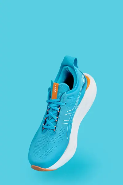 stock image Single blue Asics Gel-Nimbus 25 sport sneaker against solid blue background. Stylish fashionable minimalism concept. Flying shoes