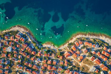 Turkuvaz suyu ve kırmızı çatılı evleri olan kıyı şehrinin deniz manzarası. Hırvatistan 'ın Adriyatik Denizi kıyısındaki Rogoznica kentinin panoraması. Yaz tatili ve seyahat konsepti