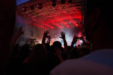 Sahnenin önündeki parlak spot ışıklarıyla konserdeki kalabalık siluetleri. İnsanlar bando konserinde canlı müzikten hoşlanırlar. Müzik festivalinde müzisyenler ve hayranlarla konser salonu