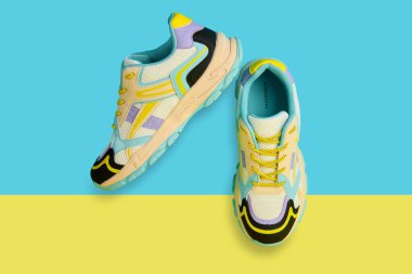 Parlak arka planda renkli aksanlı beyaz spor ayakkabılar renkli arka planda bir çift şık spor ayakkabısı. Mağaza reklamı için stüdyo fotoğrafı, yaratıcı minimalist stil.