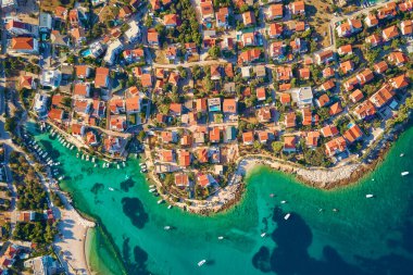 Turkuvaz suyu ve kırmızı çatılı evleri olan kıyı şehrinin deniz manzarası. Hırvatistan 'ın Adriyatik Denizi kıyısındaki Rogoznica kentinin panoraması. Yaz tatili ve seyahat konsepti