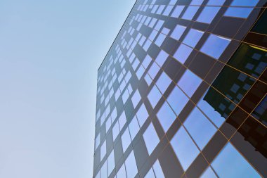 Çelik ve camdan yapılmış dış görünüşü mavi gökyüzünü yansıtan modern ofis binası. Çağdaş mimari tasarım