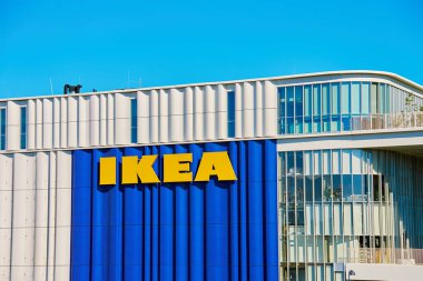 IKEA mağazasının dış cephesinde açık mavi gökyüzünün altında modern ticari bina cephesinde kalın sarı harfler var. Şehirdeki çok uluslu şirketin logosu. Kopenhag, Danimarka - 25 Haziran 2024
