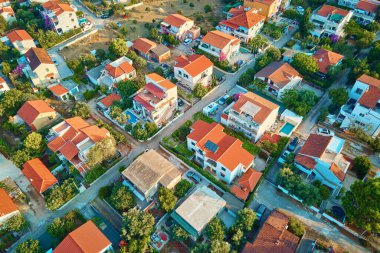 Yazın kırmızı çatılı evleri olan banliyö mahallesinin havadan görünüşü. Hırvatistan 'da renkli binaları olan küçük kıyı kasabası