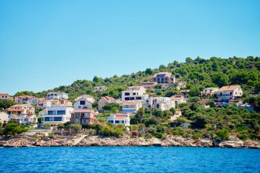 Yamaçta açık mavi sular boyunca yanaşmış tekneleri olan renkli kıyı evleri olan deniz kenarı kasabası. Hırvatistan 'ın Rogoznica kentindeki Adriyatik Denizi' nde yaz tatili için konut