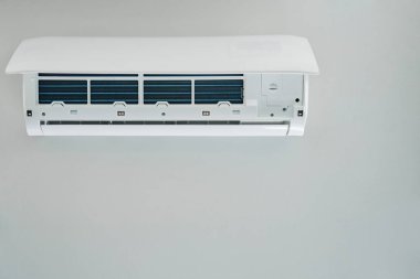 Beyaz klima ünitesi duvara monte edildi, bakım için hazır. Ön kapağı açık olan iklim sistemi iç bileşenleri açığa çıkarıyor. Apartmandaki havalandırma tamir ediliyor.