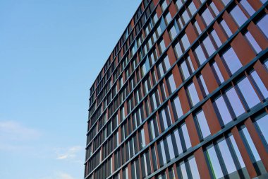 Çelik ve camdan yapılmış dış görünüşü mavi gökyüzünü yansıtan modern ofis binası. Çağdaş mimari tasarım