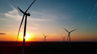 Gün batımında kırsal alanda siluetli rüzgar türbinleri. Rüzgar santrali temiz enerji üretiyor. Yenilenebilir ve sürdürülebilir enerji kavramı