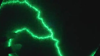 Elle plazma topuna dokunmak, canlı yeşil ışık desenleri oluşturur. Bilim sergisinde statik elektrik modeli