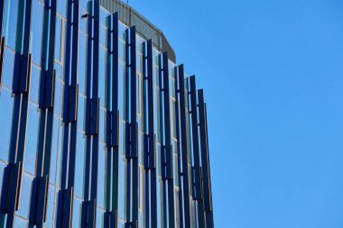 Gökyüzünü yansıtan geometrik desenli modern cam bina cephesine yakın çekim. Çağdaş mimari tasarım.