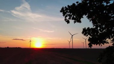 Gün batımında kırsal alanda siluetli rüzgar türbinleri. Rüzgar santrali temiz enerji üretiyor. Yenilenebilir ve sürdürülebilir enerji kavramı