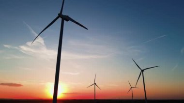 Kırsal alanda siluetli rüzgar türbinleri. Rüzgar santrali temiz enerji üretiyor. Günbatımında rüzgar çiftliği. Yenilenebilir ve sürdürülebilir enerji kavramı