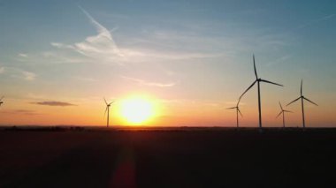 Gün batımında kırsal alanda siluetli rüzgar türbinleri. Rüzgar santrali temiz enerji üretiyor. Yenilenebilir ve sürdürülebilir enerji kavramı