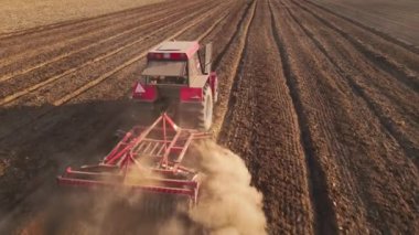Kırmızı traktör tarlada çalışıyor, kuru toprak ekip biçiyor, hava manzarası var. Tarım sektörü konsepti. Küçük tarım kavramı