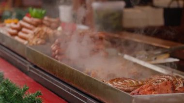 Sokak satıcısı Polonya, Wroclaw 'daki Noel pazarında ızgarada sosis hazırlıyor. Sokak yemeklerini pişirme süreci