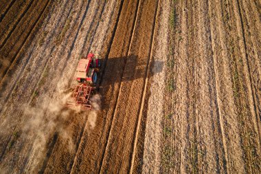 Kırmızı traktör tarlada çalışıyor, kuru toprak ekip biçiyor, hava manzarası var. Tarım sektörü konsepti. Küçük tarım kavramı