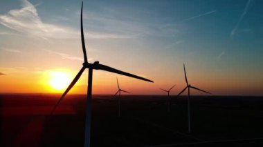 Kırsal alanda siluetli rüzgar türbinleri. Rüzgar santrali temiz enerji üretiyor. Günbatımında rüzgar çiftliği. Yenilenebilir ve sürdürülebilir enerji kavramı