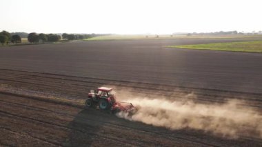 Kırmızı traktör tarlada çalışıyor, kuru toprak ekip biçiyor, hava manzarası var. Tarım sektörü konsepti. Küçük tarım kavramı