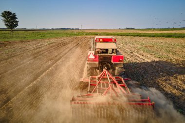 Kırmızı traktör tarlada çalışıyor, kuru toprak ekip biçiyor, hava manzarası var. Tarım sektörü konsepti. Küçük tarım kavramı