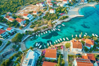 Deniz kıyısında kuş bakışı manzara ve deniz kıyısında küçük bir kasaba. Kırmızı çatılı evleri ve kıyıya yakın tekneleri olan kıyı köyünün havadan görünüşü. Hırvatistan 'ın Adriyatik Denizi üzerindeki Rogoznica kasabası
