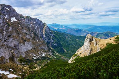 Kayalık kayalıkları ve karla kaplı engebeli bir dağ yamacı. Polonya 'daki Tatra Ulusal Parkı. Doğal manzara.