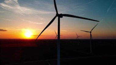 Gün batımında kırsal alanda siluetli rüzgar türbinleri. Rüzgar santrali temiz enerji üretiyor. Yenilenebilir ve sürdürülebilir enerji kavramı
