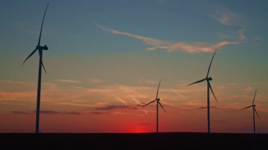 Kırsal alanda siluetli rüzgar türbinleri. Rüzgar santrali temiz enerji üretiyor. Günbatımında rüzgar çiftliği. Yenilenebilir ve sürdürülebilir enerji kavramı