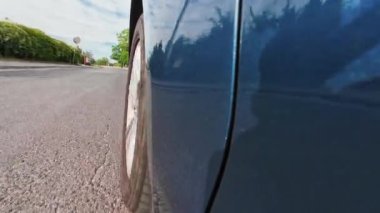 Caddedeki asfalt yolda araba sürerken yakın plan görüntüsü. Aracın tekerlek dönme hareketi