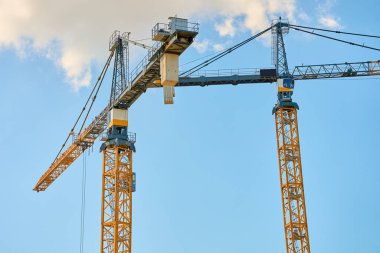 Açık mavi gökyüzüne karşı inşaat vinci. Yeni konutların inşası ve kentsel altyapının geliştirilmesi