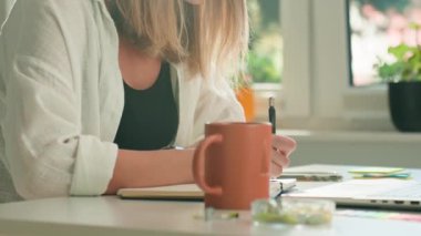Evden uzakta çalışan bir kadın. Serbest çalışan kadın kahve içiyor ve iş yerinde dizüstü bilgisayar kullanıyor. Serbest çalışma kavramı ve uzak çalışma