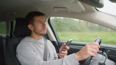 Sürücü araba kullanırken akıllı telefon kullanıyor, telefonundaki mesajlar dikkatini dağıtıyor. Tehlikeli araç kullanma, trafik kurallarının ihlali.